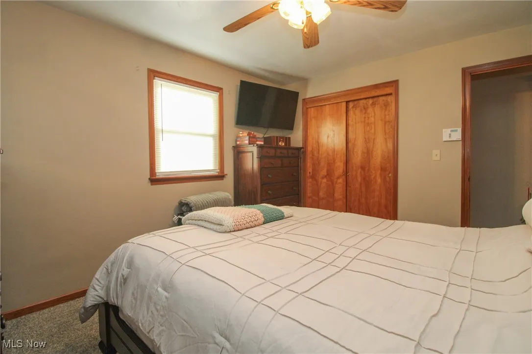 Carpeted bedroom featuring a closet and ceiling fan