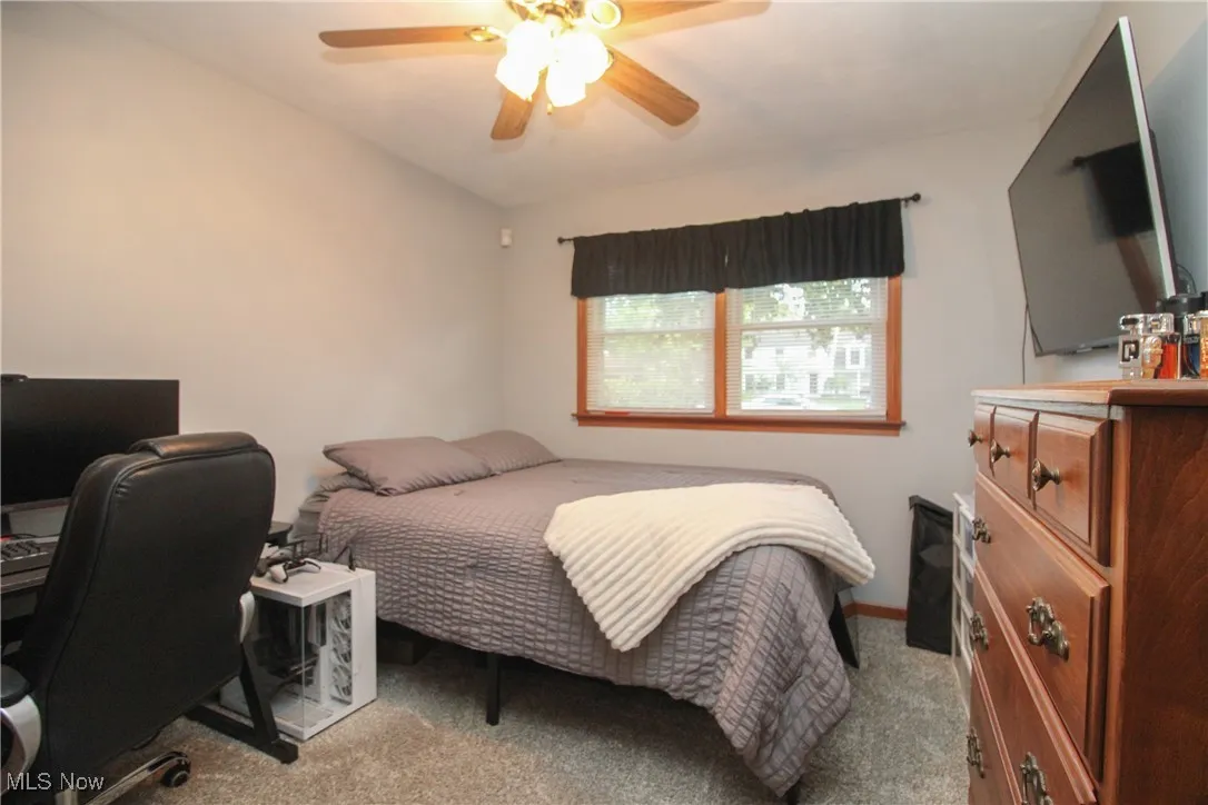 Bedroom featuring an office area, light carpet, and a ceiling fan