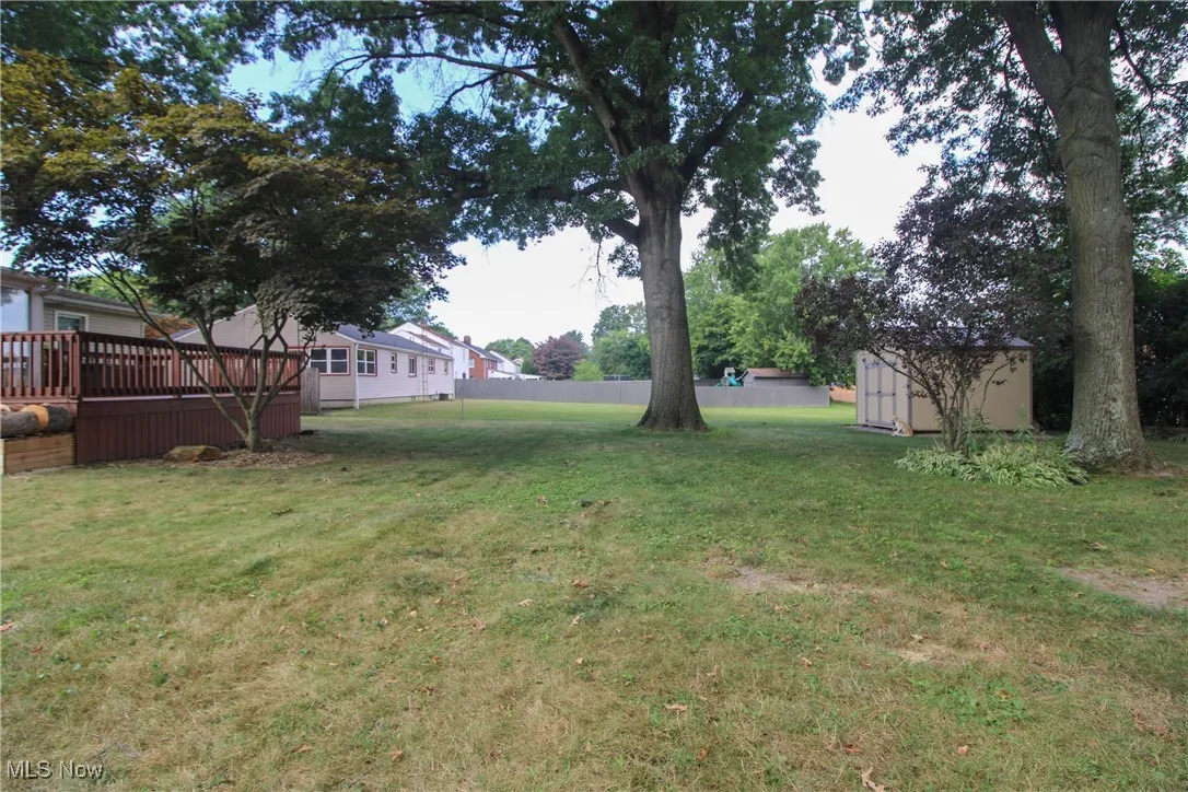 View of grassy yard with a storage shed and a wooden deck
