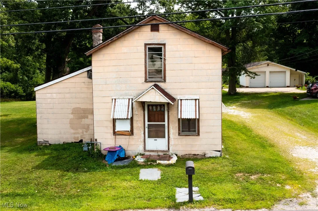 View of front of house with a front lawn, a detached garage, and an outbuilding