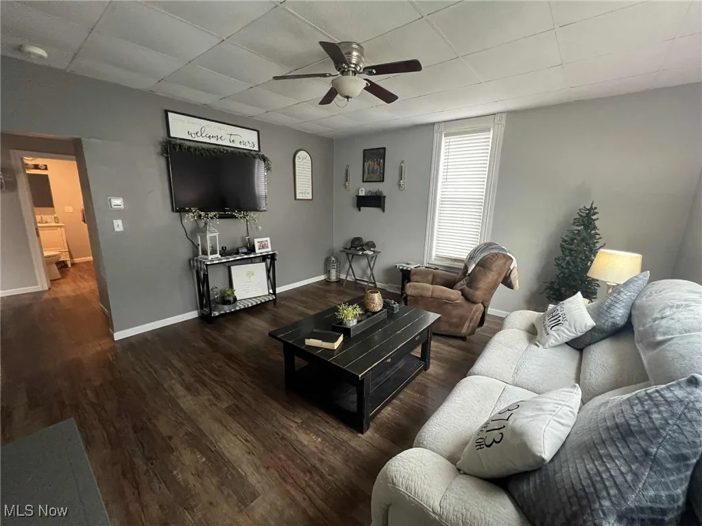 Living area featuring ceiling fan, a paneled ceiling, and wood finished floors