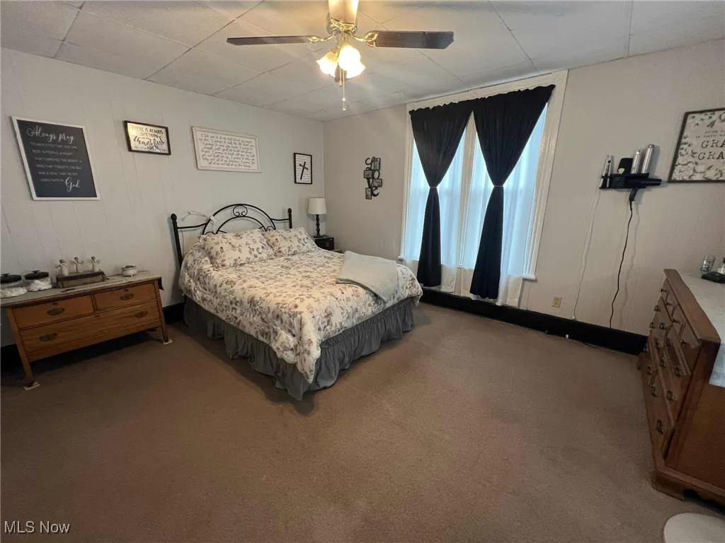 Carpeted bedroom featuring a ceiling fan