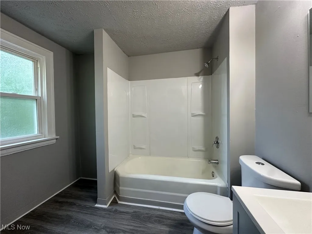 Full bath with vanity, wood finished floors, a textured ceiling, and bathing tub / shower combination