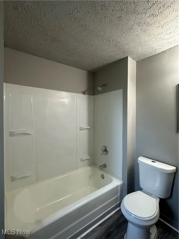 Full bath featuring a textured ceiling, wood finished floors, and shower / bathtub combination