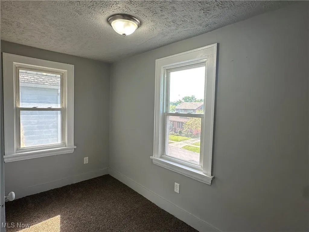 Spare room with a textured ceiling and dark carpet