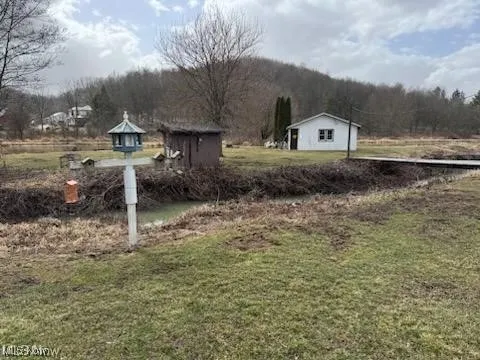 View of green lawn with an outbuilding and a view of countryside