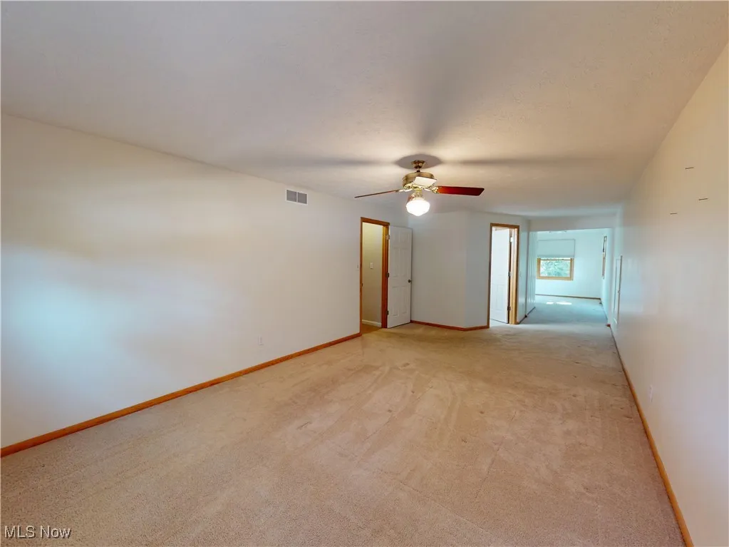 master bedroom with light colored carpet and a ceiling fan