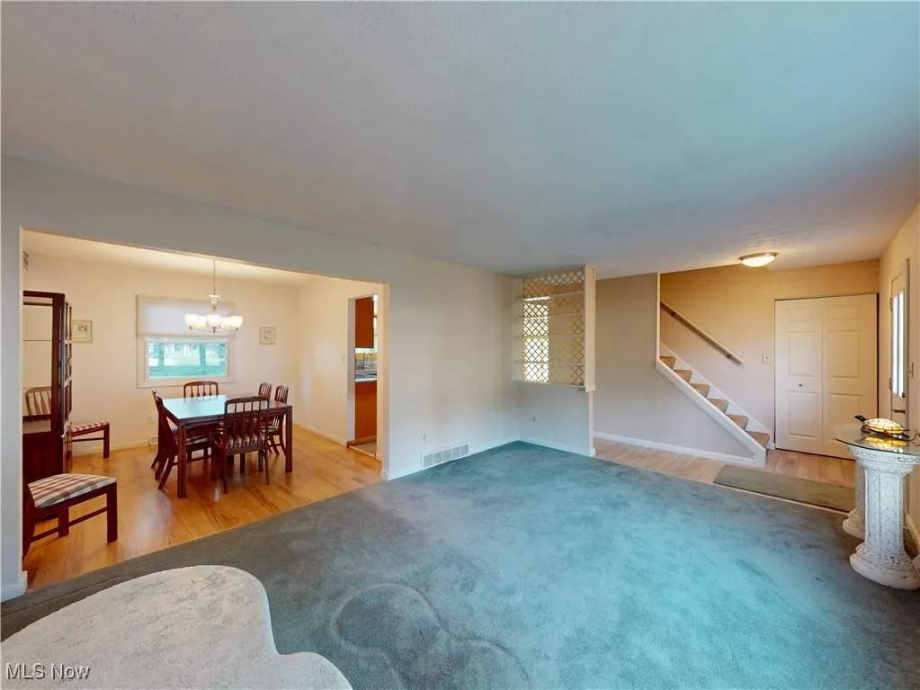Living area featuring stairway, light wood finished floors, a chandelier, and light carpet