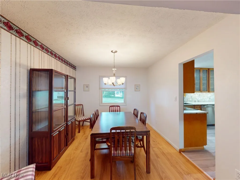 Dining space with light wood-style flooring, a textured ceiling, and a chandelier