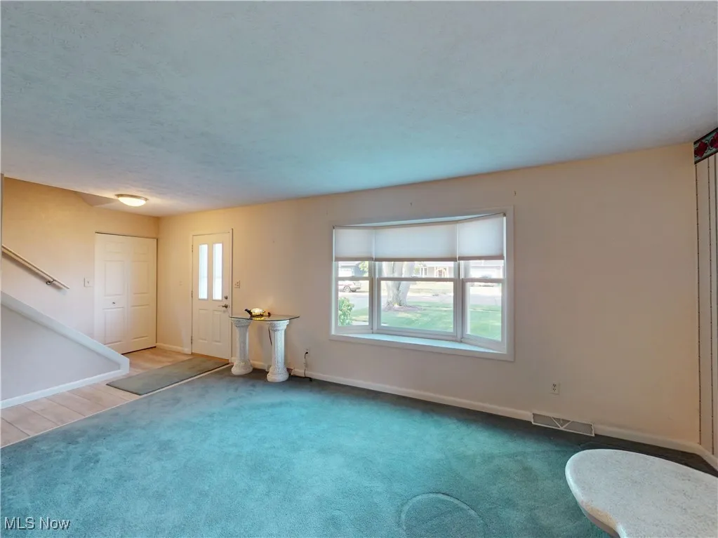 Unfurnished living room with carpet and a textured ceiling