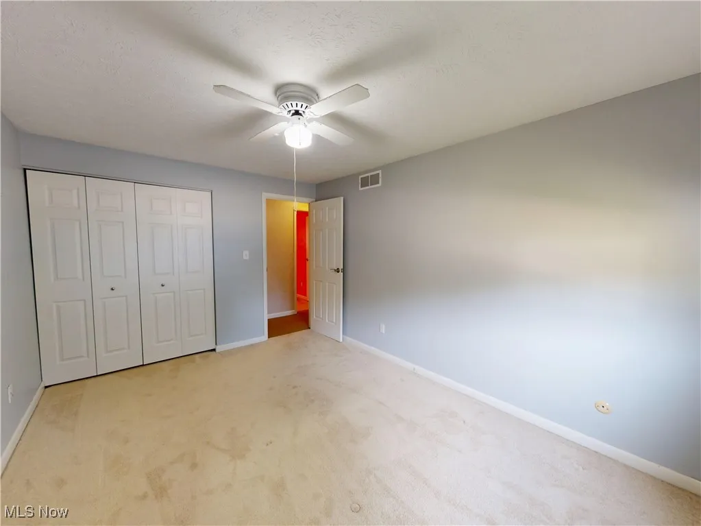  bedroom featuring light colored carpet, a closet, a textured ceiling, and a ceiling fan