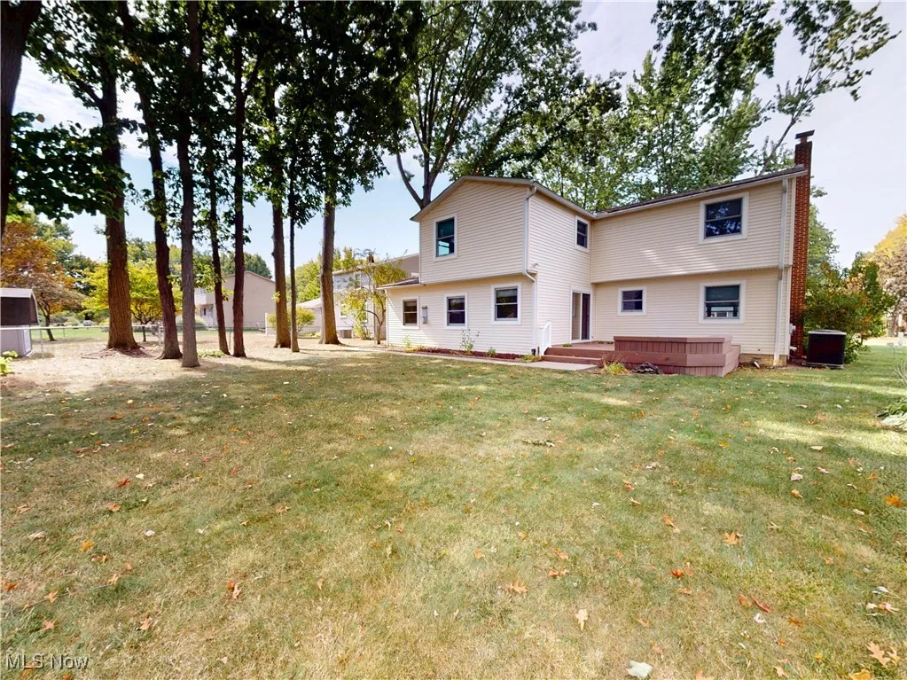 Back of property with a chimney, a yard, and a deck