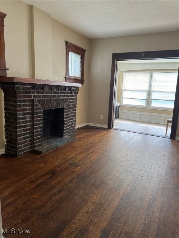 Unfurnished living room with dark wood-type flooring, a fireplace, and a textured ceiling