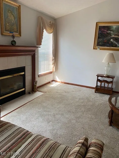 Living room with carpet flooring, a tile fireplace, and a textured ceiling