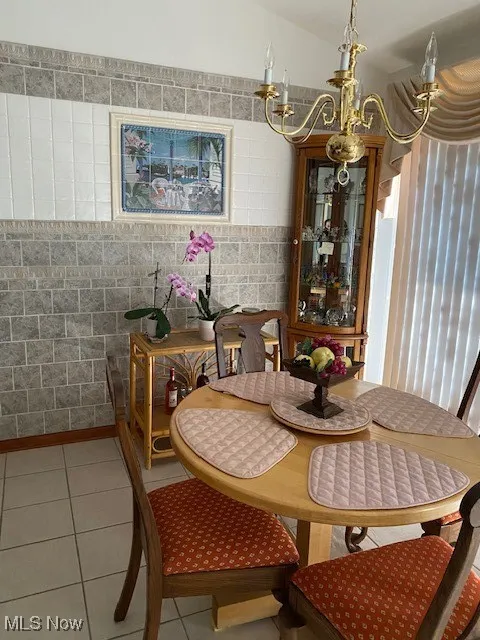 Dining room featuring tile patterned floors, tile walls, and a chandelier
