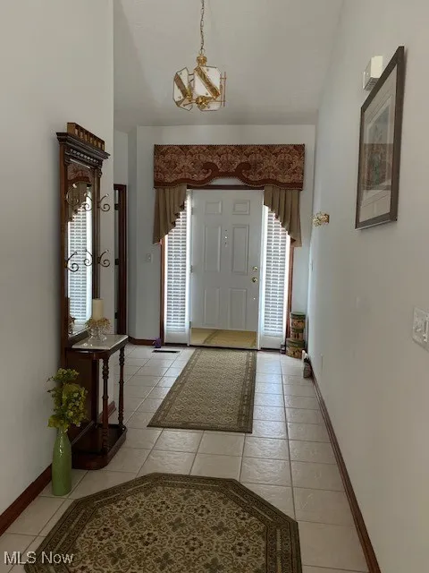 Foyer entrance featuring a chandelier, light tile patterned flooring, and vaulted ceiling