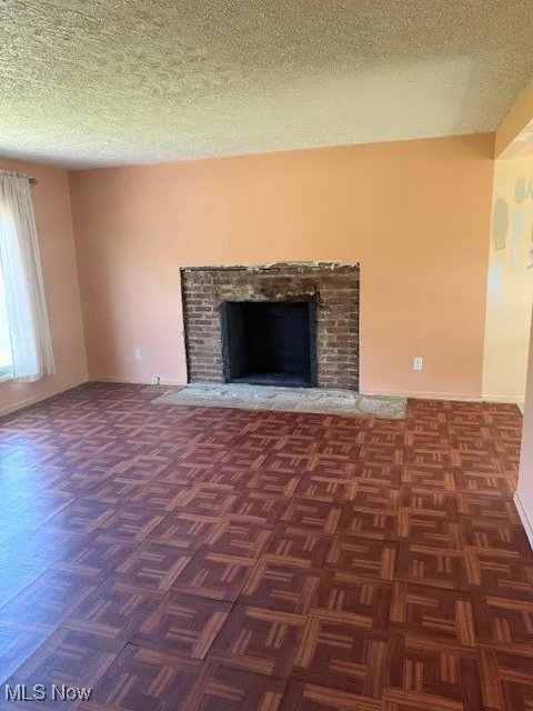 Unfurnished living room featuring a textured ceiling and a fireplace