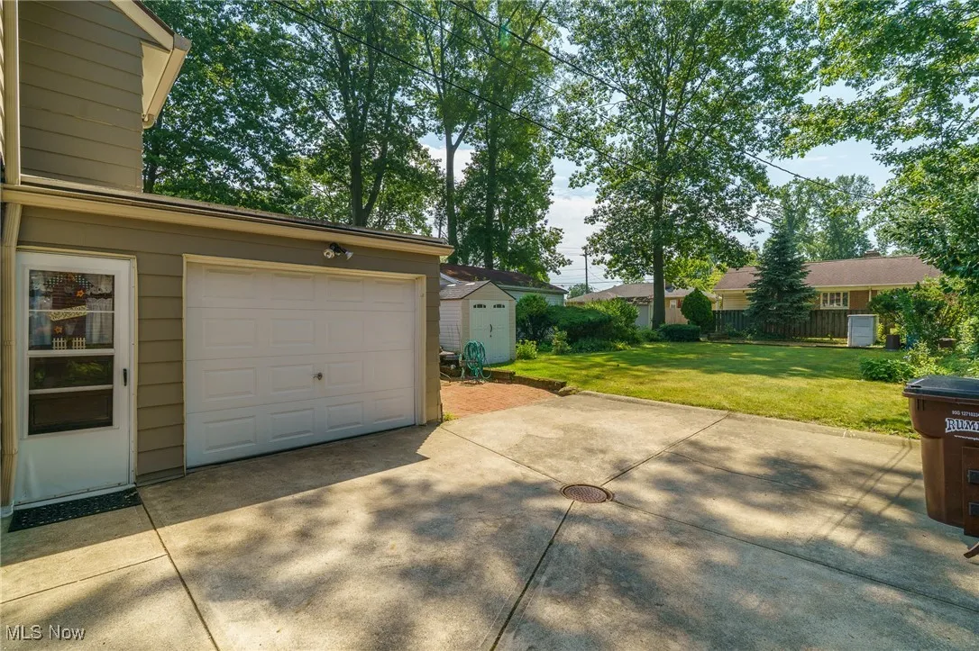 Attached garage with lots of parking area, brick patio and storage shed
