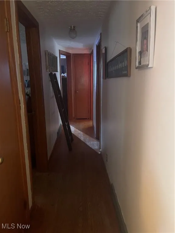 Hall with a textured ceiling and dark wood finished floors