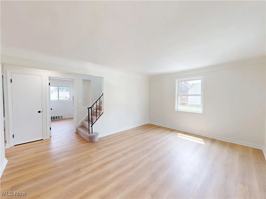 Empty room with stairs and light wood-type flooring