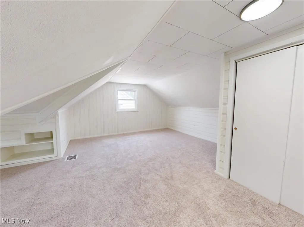 Additional living space with carpet and vaulted ceiling