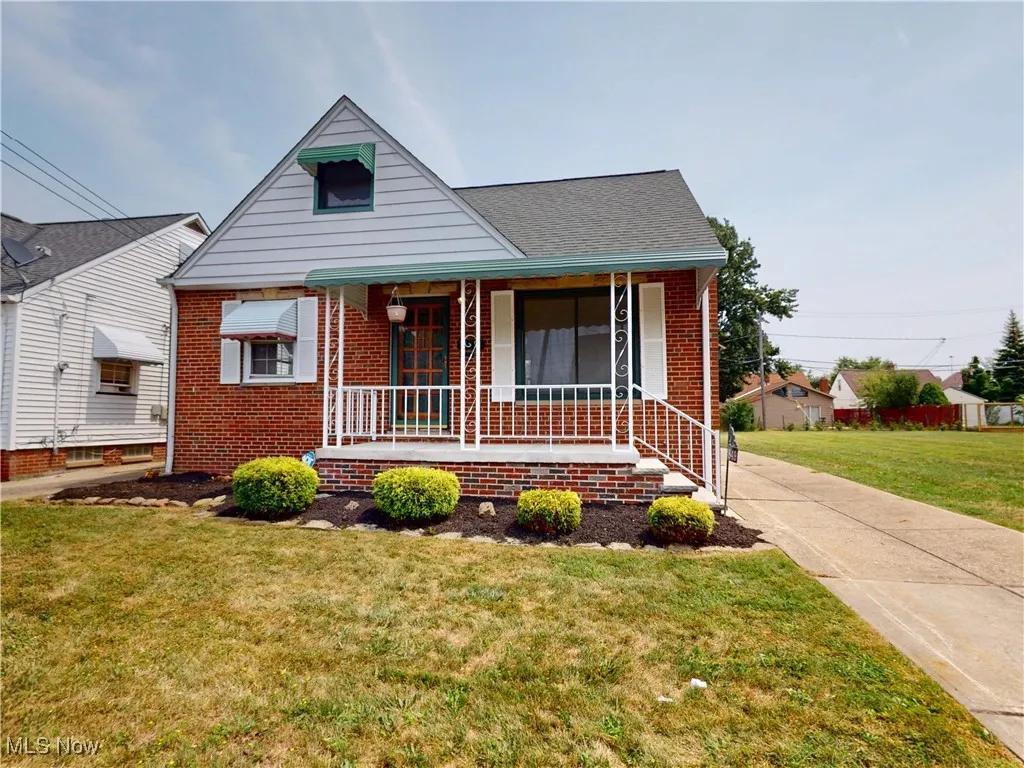 Bungalow-style house with covered porch, brick siding, a front lawn, and a shingled roof