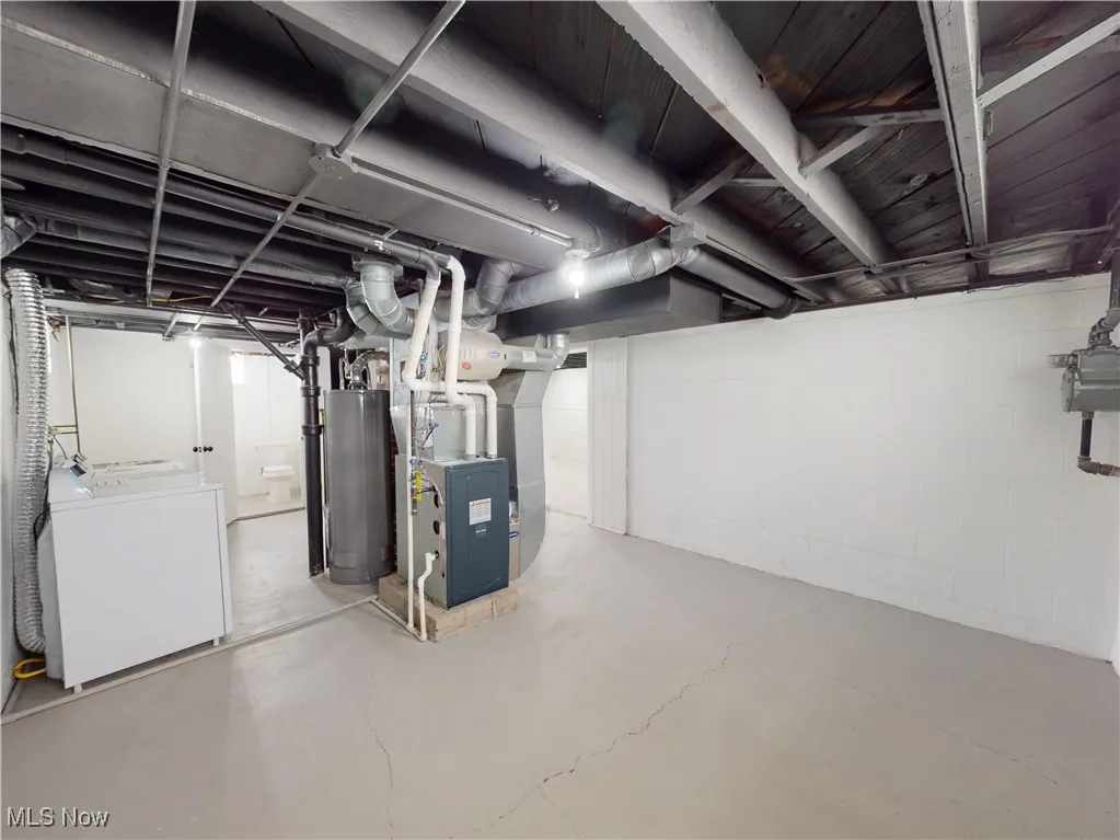 Unfinished basement featuring washer / clothes dryer, water heater, and heating unit