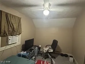 Bedroom with lofted ceiling, ceiling fan, cooling unit, and a textured ceiling
