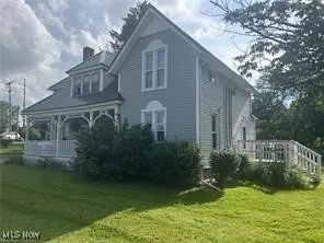 Rear view of house featuring a yard, a chimney, and a porch