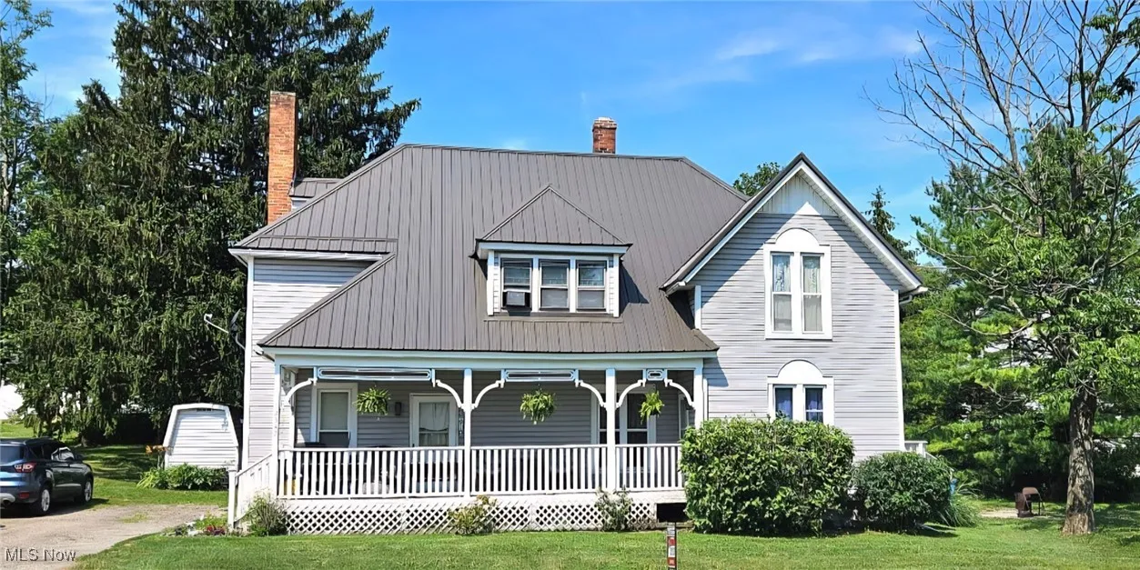 View of front of home featuring a porch, a front lawn, a metal roof, and a chimney