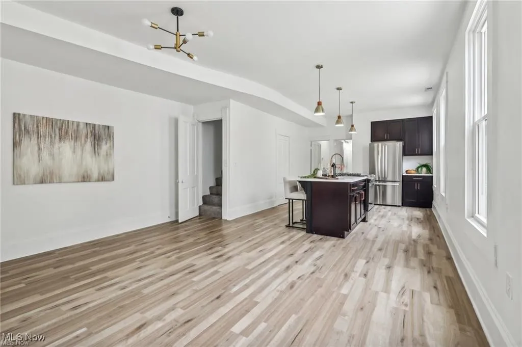 Kitchen featuring freestanding refrigerator, a breakfast bar, light wood-style flooring, light countertops, and an island with sink