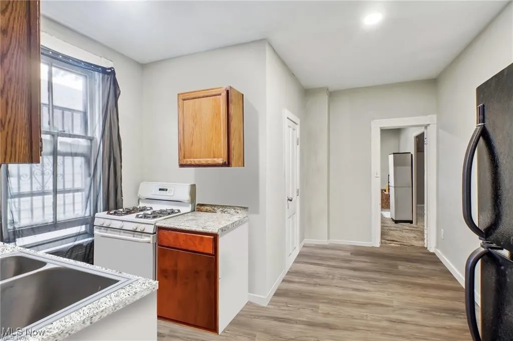 Kitchen with white appliances, light wood finished floors, light countertops, and brown cabinetry