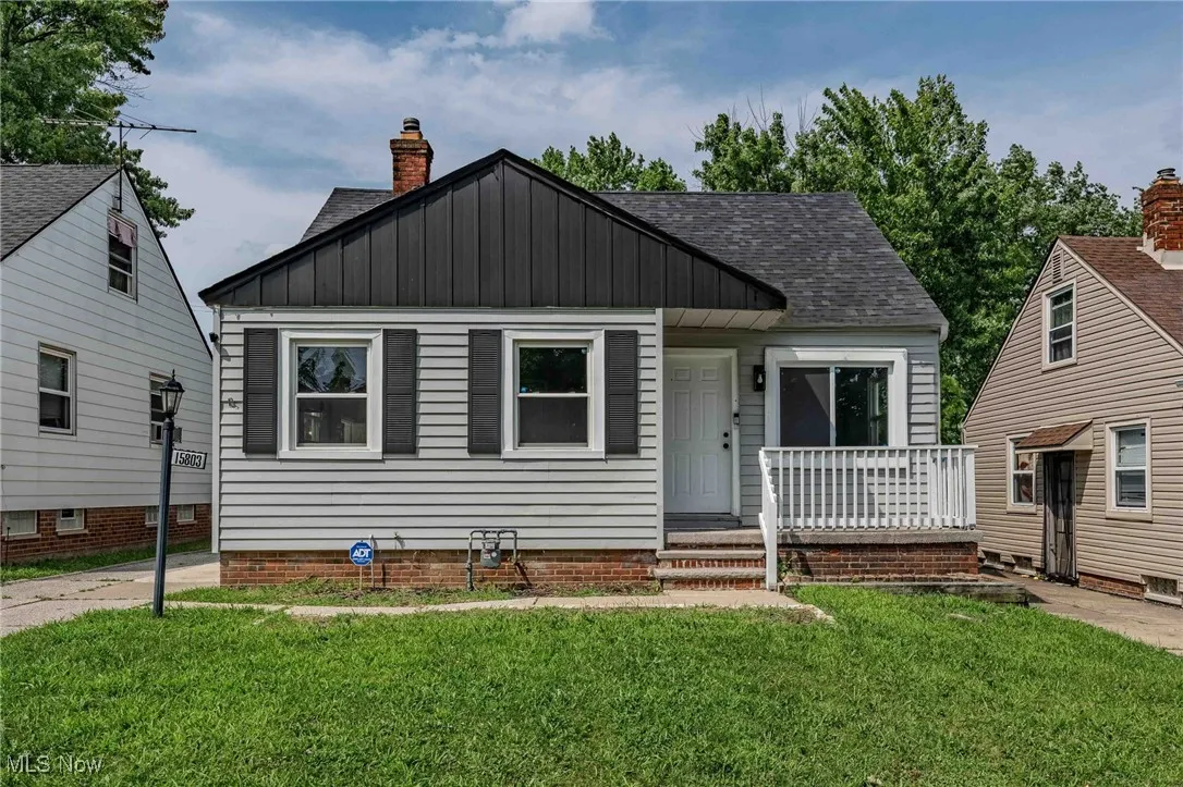 Bungalow-style house featuring board and batten siding, a shingled roof, a front yard, a porch, and a chimney