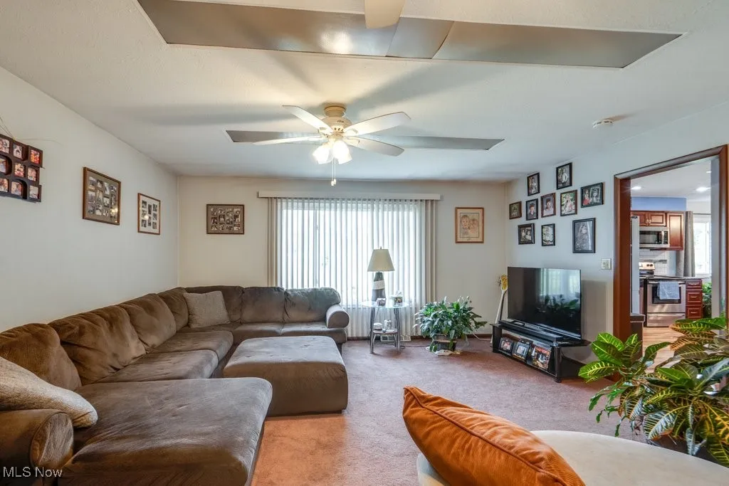 Carpeted living room featuring a ceiling fan