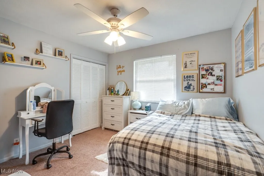 Bedroom featuring a closet, a desk, light carpet, and a ceiling fan