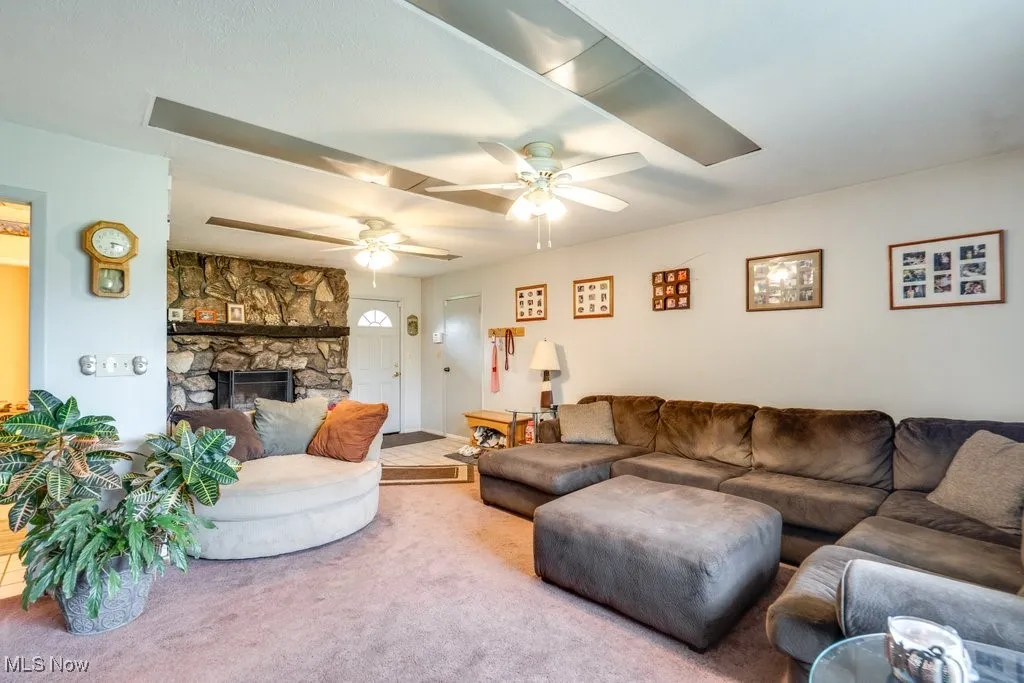 Living room with carpet and a stone fireplace