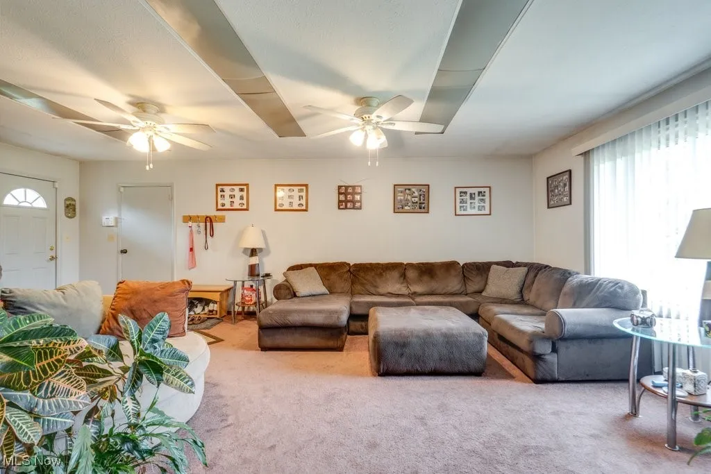 Carpeted living area featuring a ceiling fan