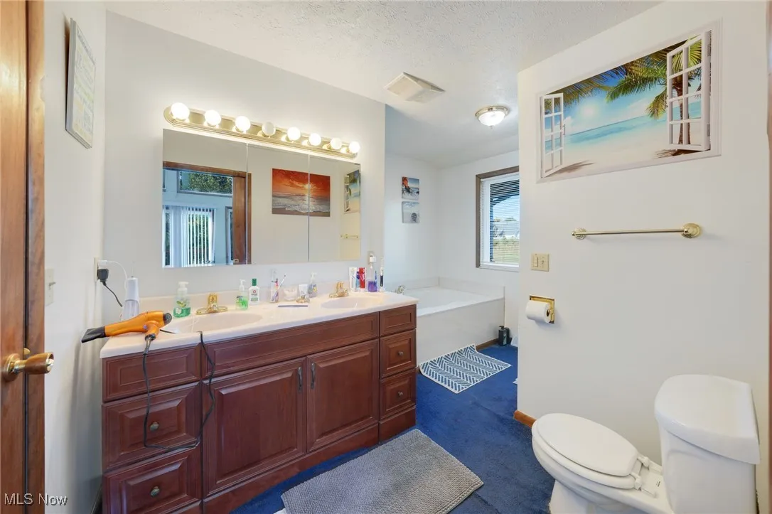 Bathroom with a garden tub, double vanity, and a textured ceiling