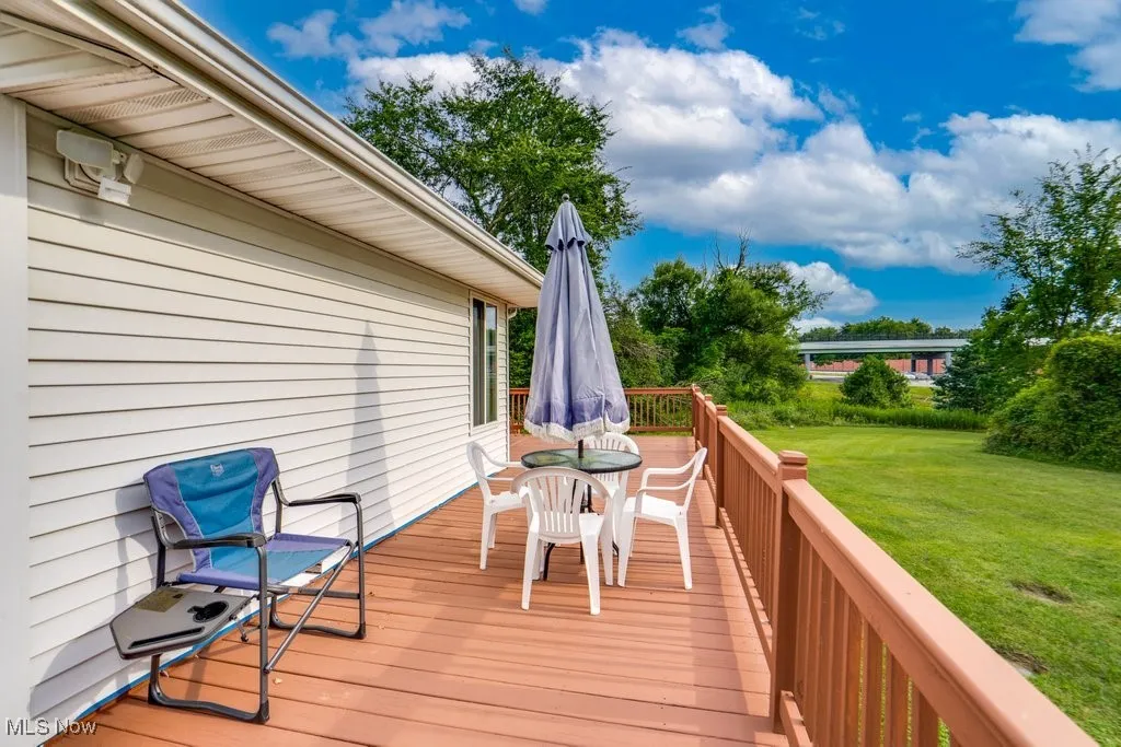 Wooden deck with outdoor dining space and a yard
