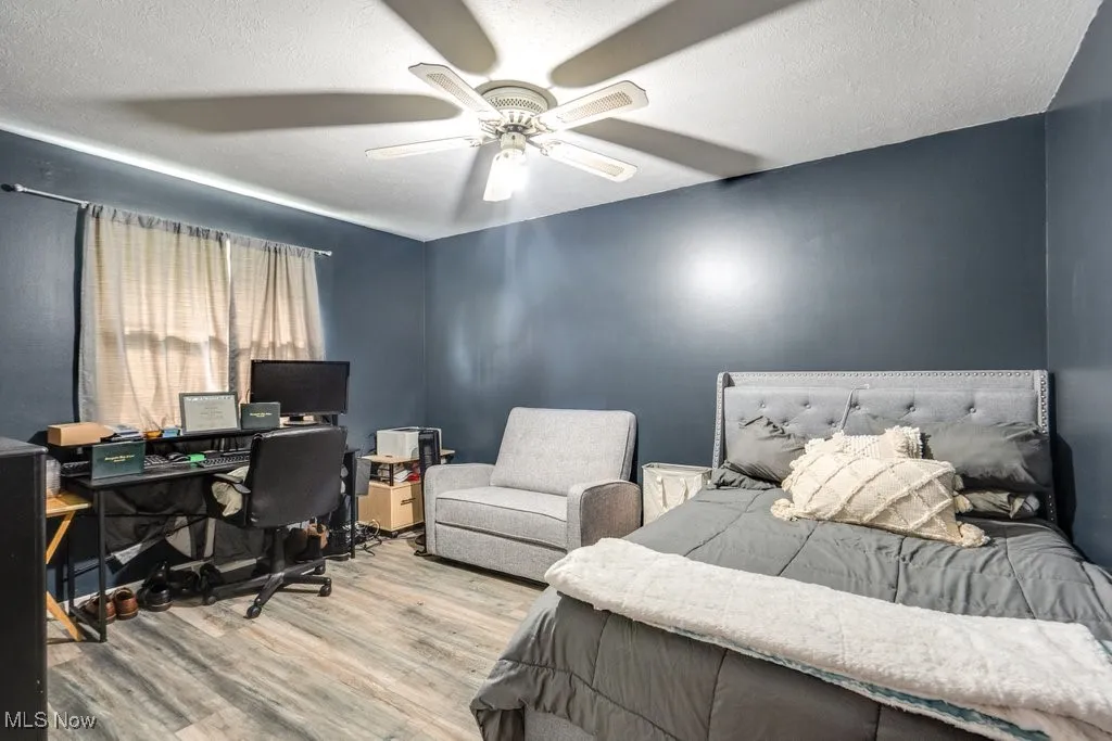 Bedroom featuring a desk, a textured ceiling, wood finished floors, and a ceiling fan