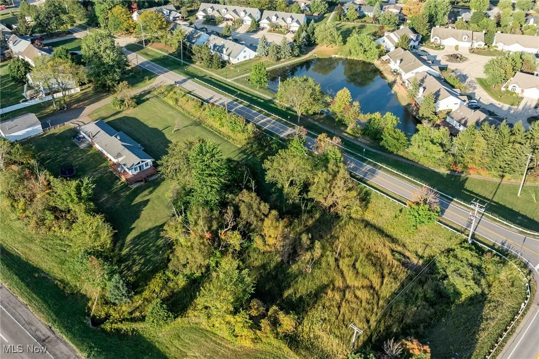 Aerial view of property and surrounding area featuring nearby suburban area and a large body of water