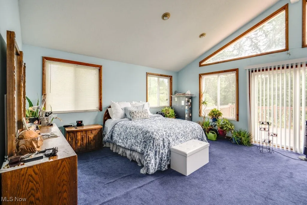 Bedroom with dark colored carpet and lofted ceiling