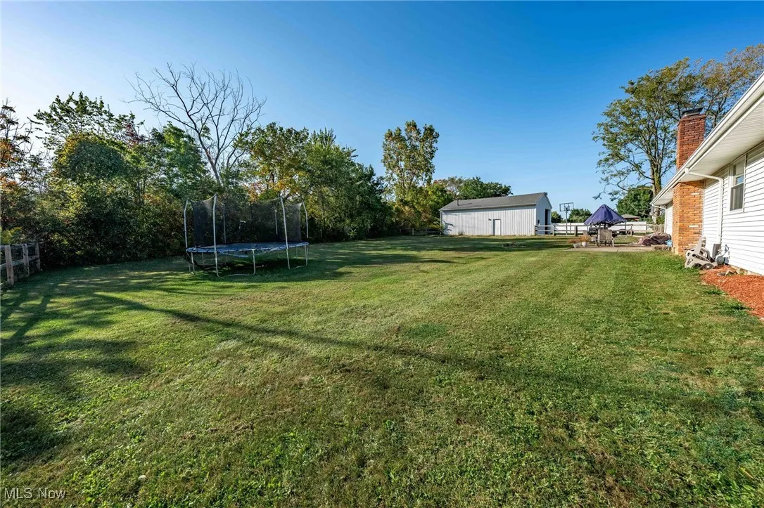 View of grassy yard featuring a trampoline