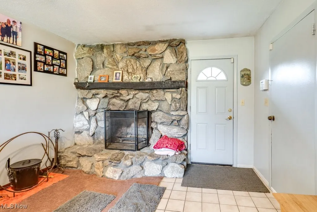 Tiled entryway featuring a stone fireplace and a textured ceiling