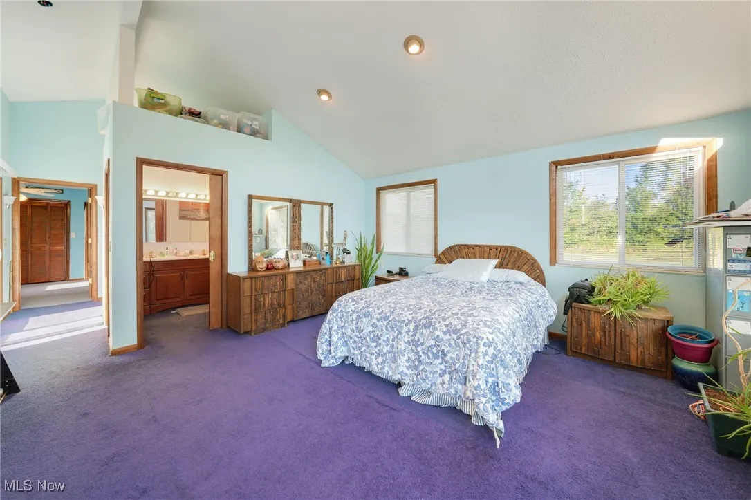 Bedroom featuring carpet flooring, recessed lighting, high vaulted ceiling, and ensuite bath