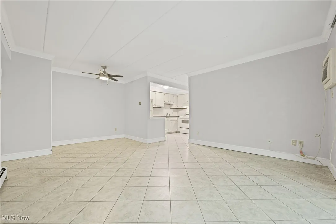 Unfurnished living room featuring crown molding, ceiling fan, and light tile patterned floors