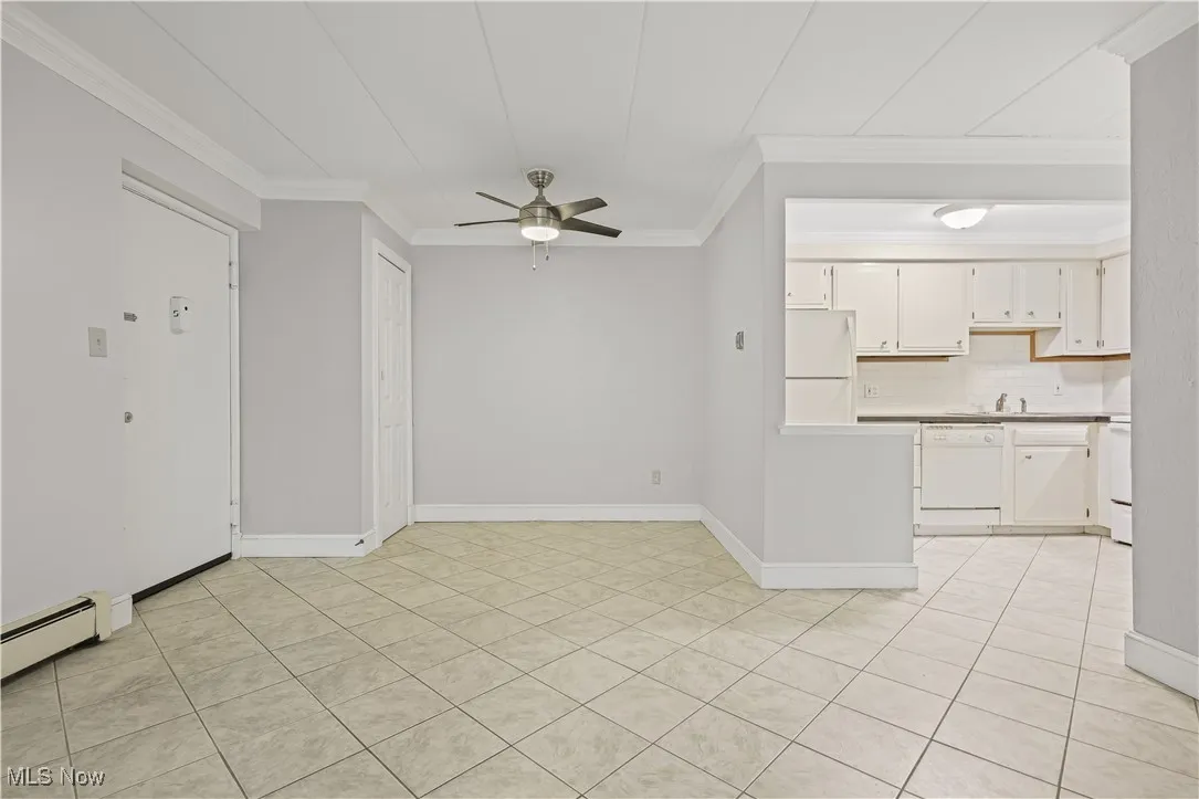 Kitchen with light countertops, white appliances, a ceiling fan, crown molding, and backsplash