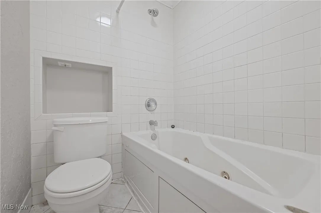 Full bath featuring tile walls, tile patterned floors, and a combined bath / shower with jetted tub