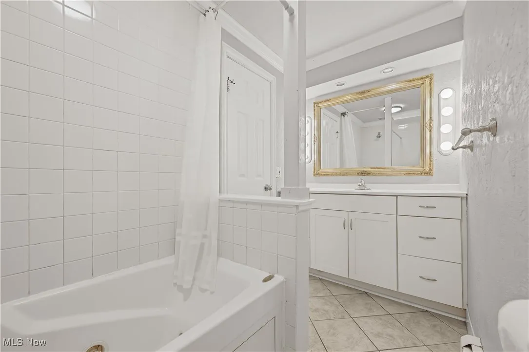 Full bathroom featuring tile patterned flooring, shower / bathtub combination with curtain, and vanity