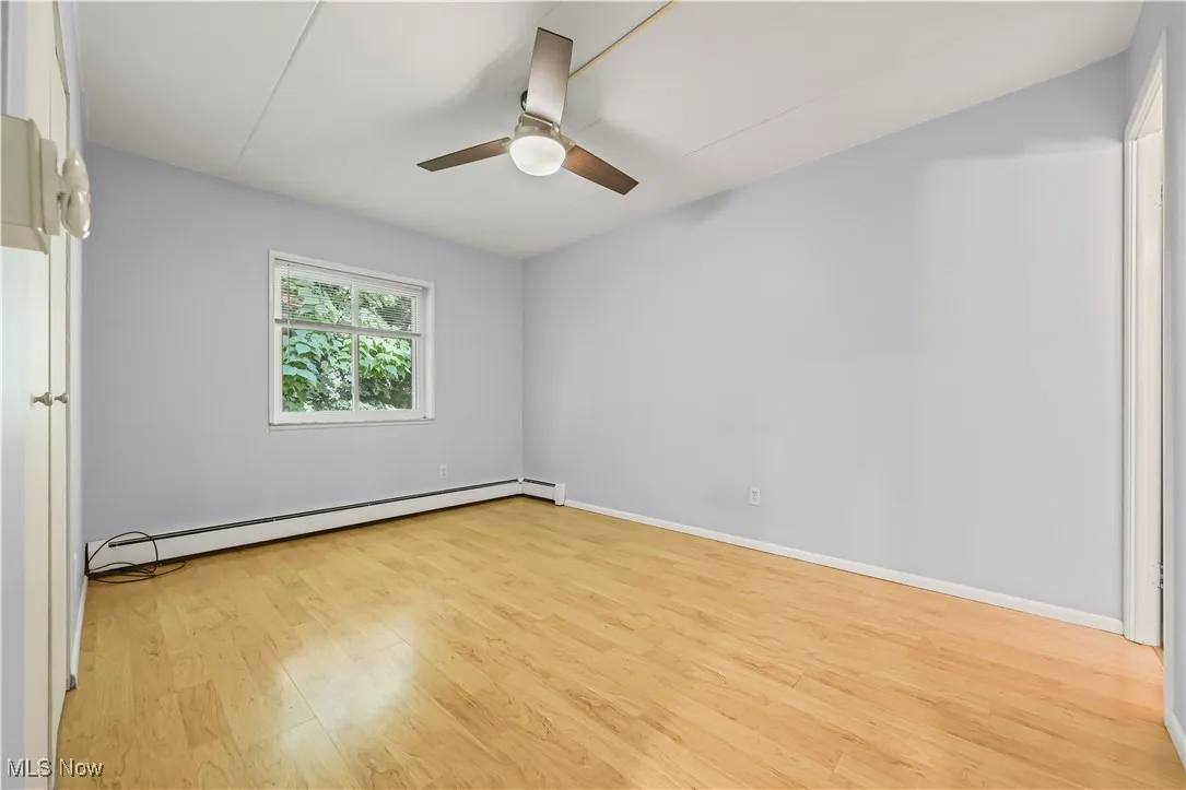 Unfurnished room with light wood-type flooring, a baseboard heating unit, and a ceiling fan